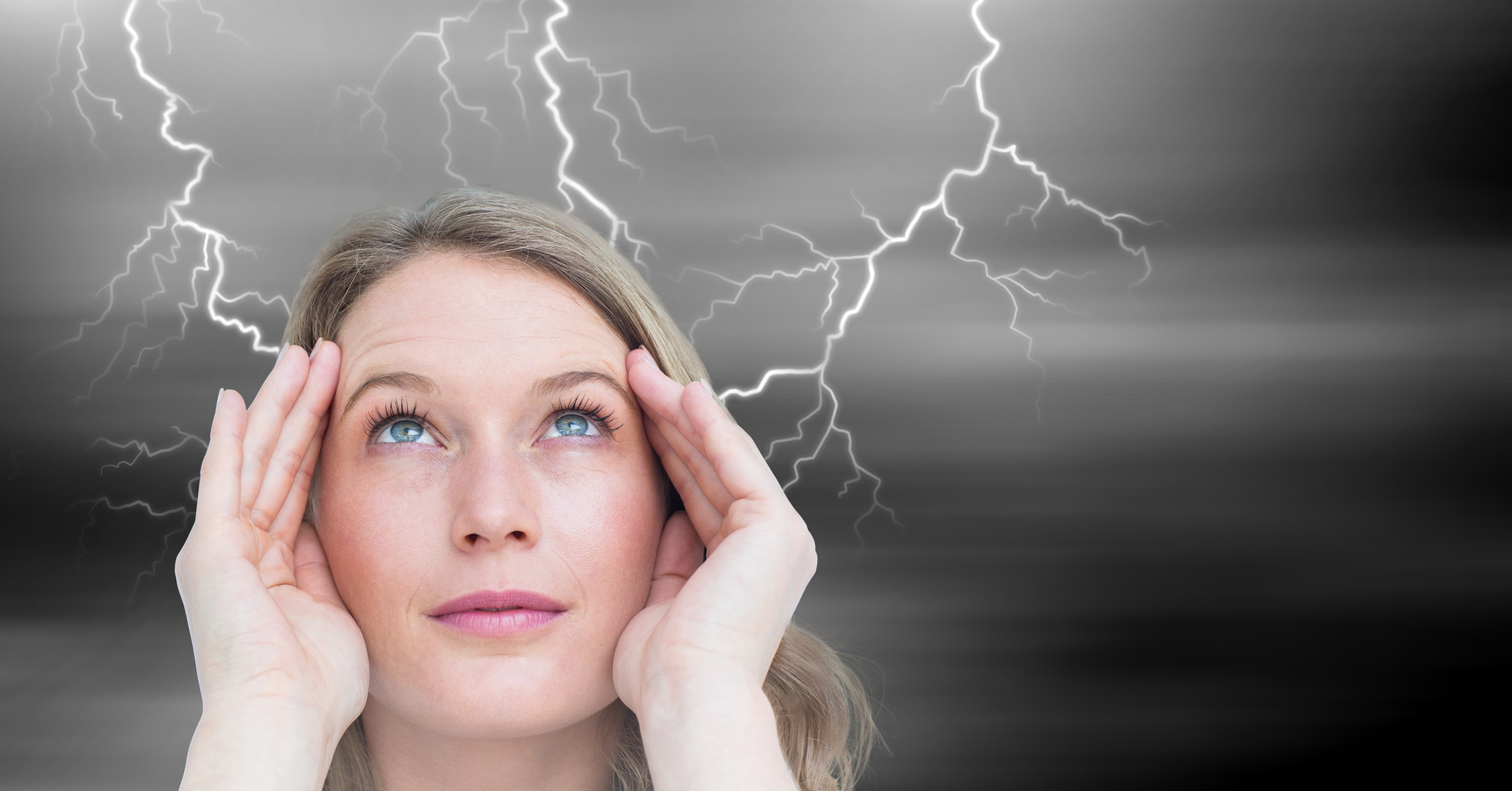 close up of woman's face with headache and lightening in background