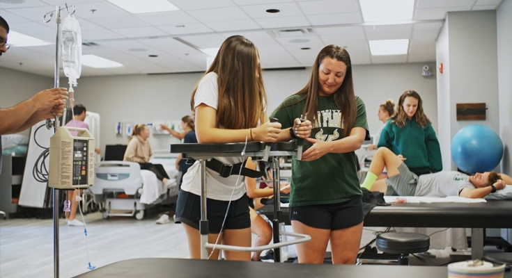 one person helps another person use a physical therapy tool