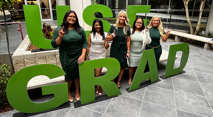 Women posing with grad signage.