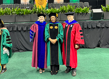 Two women and a man posing in graduation attire