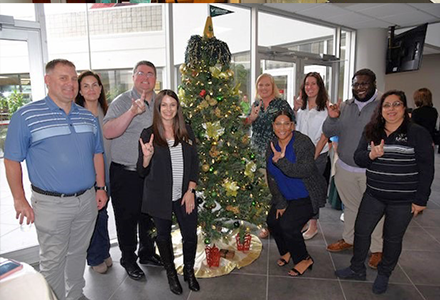 A group of people pose for the camera in front of a Christmas tree