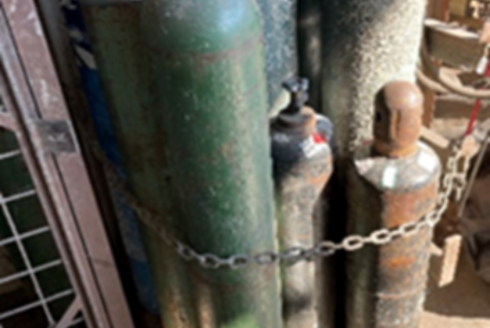 An oxygen cylinder is stored immediately next to a fuel-gas cylinder in a welding area.