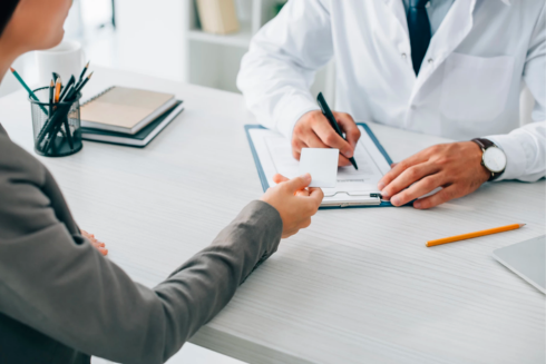 Woman handing card to man in lab coat with clipboard