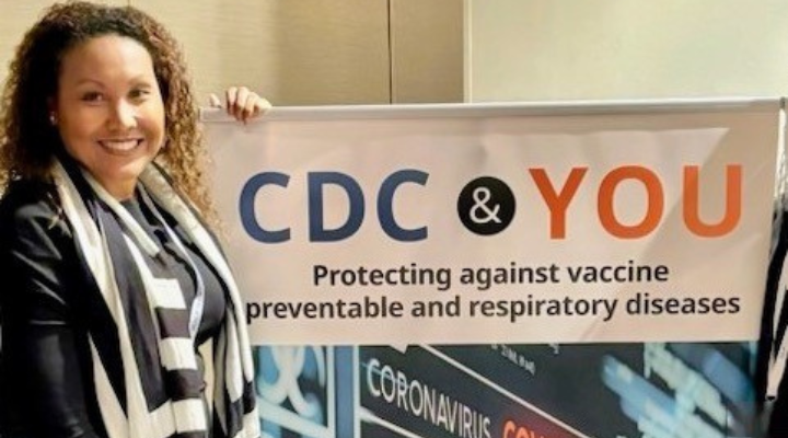 A woman standing with a CDC sign