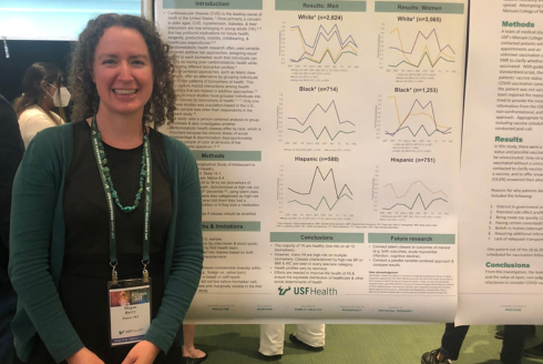 Woman in green standing in front of research poster