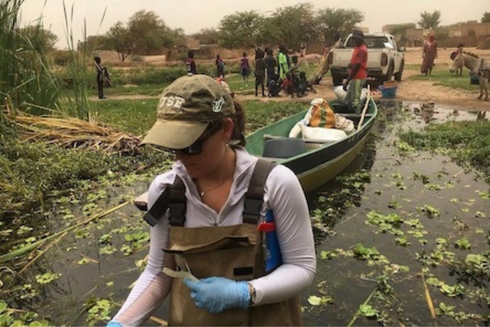 Woman with baseball cap wading in river