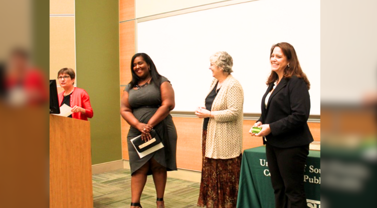 a woman at a podium giving a certificate to another woman