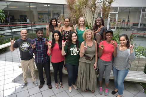 Dean Petersen standing with group of students outside flashing USF Bulls hand sign.