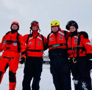 4 people standing in snow dry suits