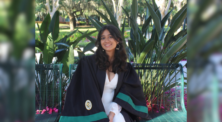 woman in graduation gown on bench