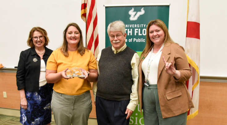 a woman holding an award with 3 other people