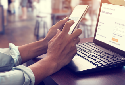 Man looking at phone and computer