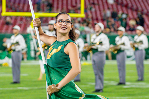 Young woman with glasses on football field spinning a large flag