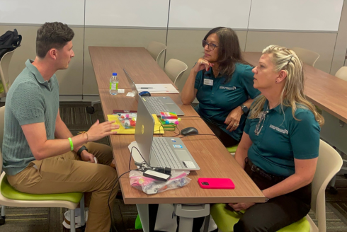three people talking at a work table