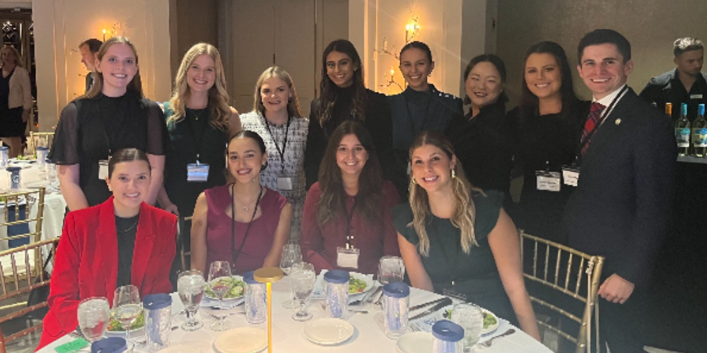 group of people standing an sitting around a dinner table at a function
