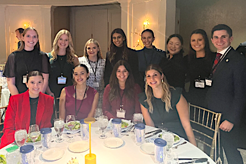 group of people standing an sitting around a dinner table at a function