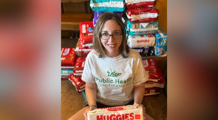 a person smiling holding diaper packages