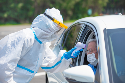 man in hazmat suit getting temperature of man in car