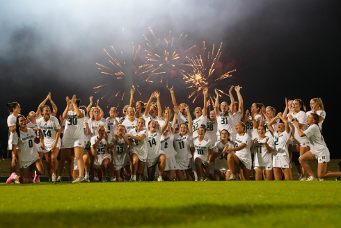 women's lacrosse team in front of fireworks