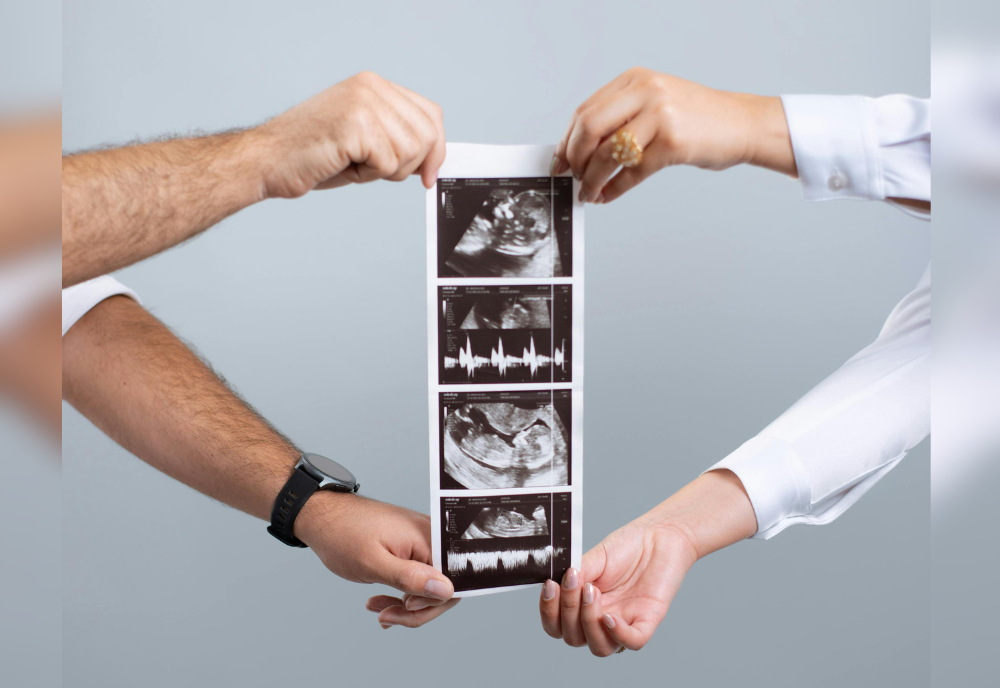 A couple's hands holding up ultrasound scans.
