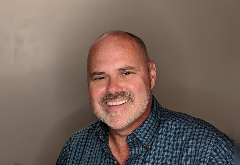 David Krause smiling in front of a blank wall.