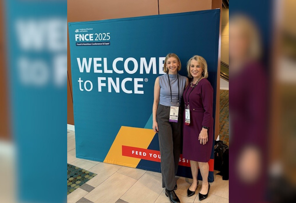 Dr Lauri Wright standing at the FNCE 2025 conference with a colleague.