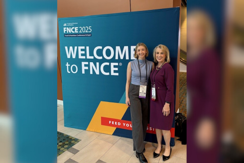 Dr Lauri Wright standing at the FNCE 2025 conference with a colleague.