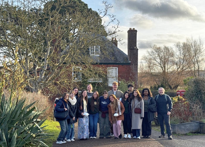 A group of students posing alongside Dr. Benjamin Young in front of a cottage during the Semester in England program.