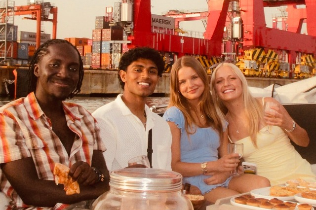 Abhi Muthiraparambath sits alongside three of his peers on a boat as they enjoy a meal together.