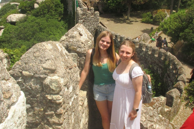 Kaileigh Moran stands alongside Emily Meeker as they pose for a photo with the Portugal scenery in the background.