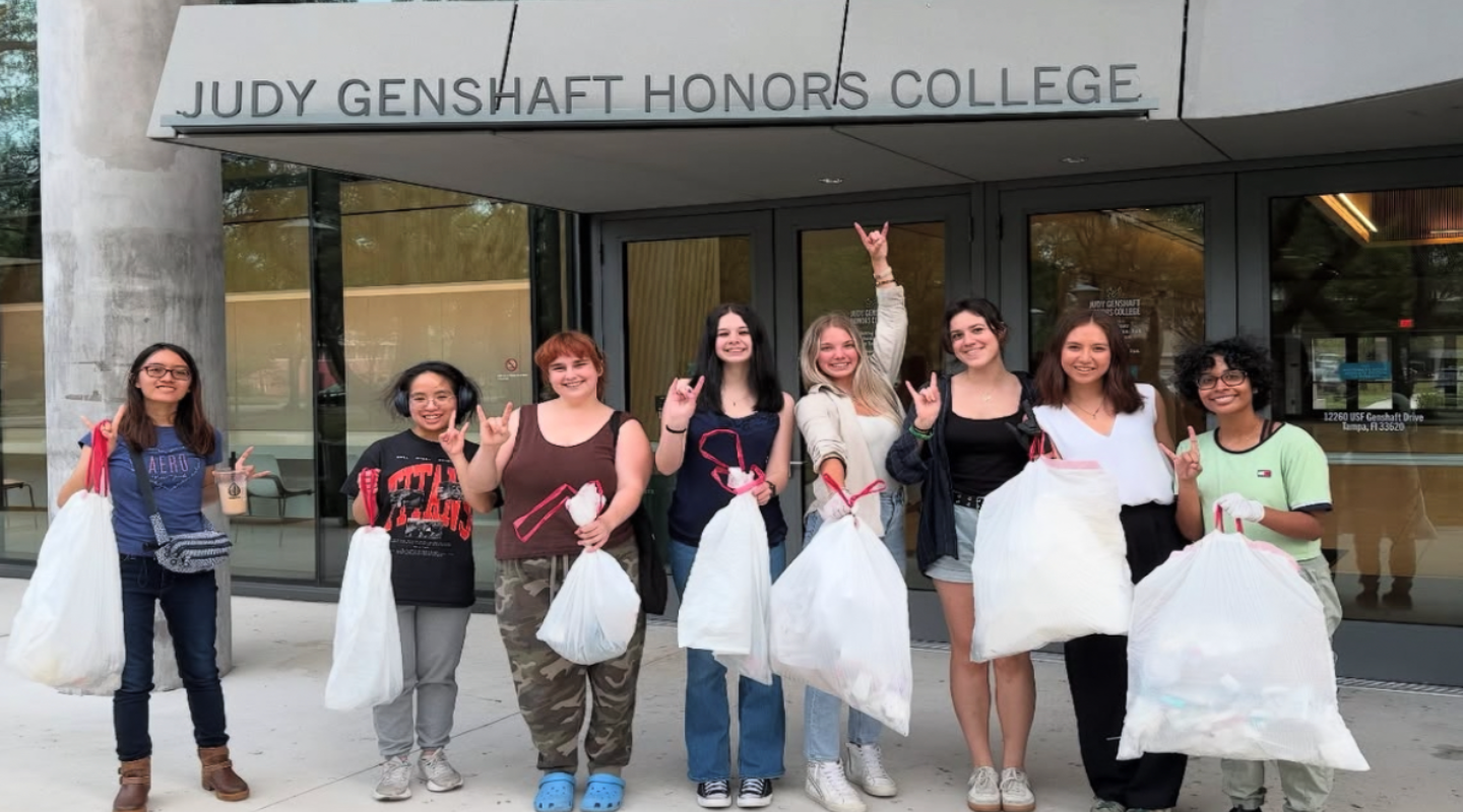 Climate-Teach in participants hold up trash bags in front of the Judy Genshaft Honors College building