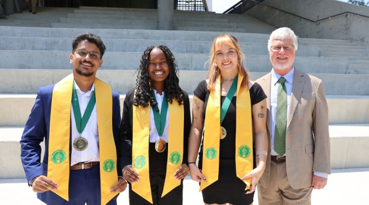 Ankit Patel, K'yana Edwards, and Nora Wolfgang (Dean Circle of Merit Winners) pose outside the Honors building at graduation with Dean Adams.