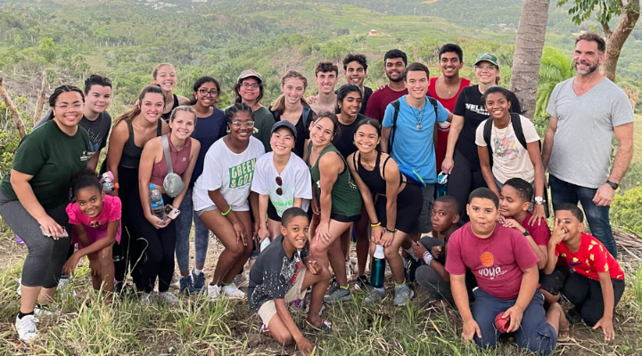Students and faculty smile with community members overlooking a peak