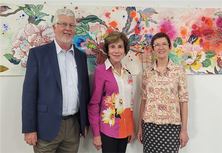 From Left to Right: Dean Charles Adams, Judy Genshaft, and Artist Elizabeth Condon stand in front of a piece featuring florals and birds