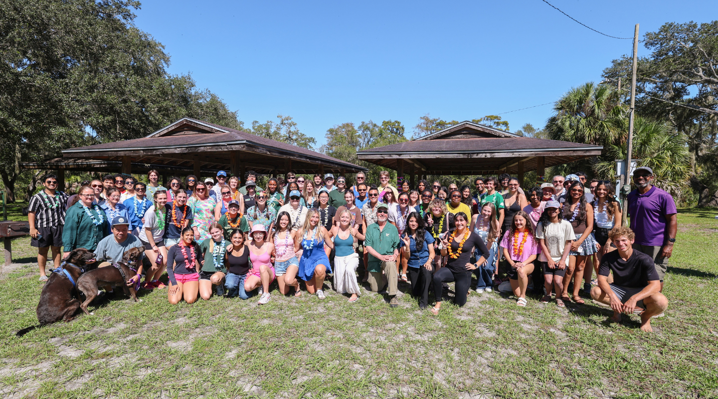Students and faculty smile for a large group photo at the honors beach bash