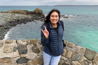 Honors student Reva Ghandi smiles in front of the ocean on the English coast.