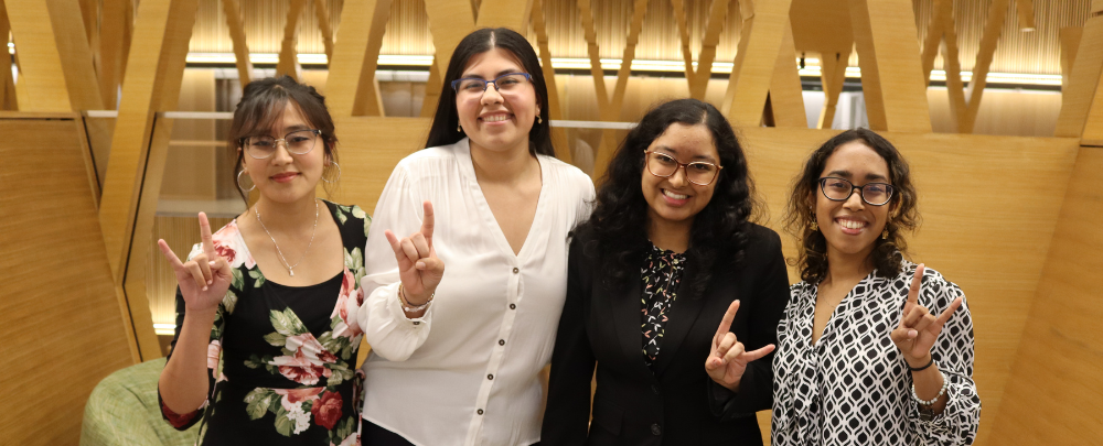 A group of students smile for a photo in front of a learning loft.