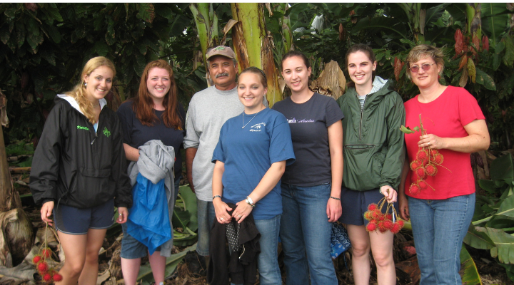 Honors students smile surrounded by lush vegtation.