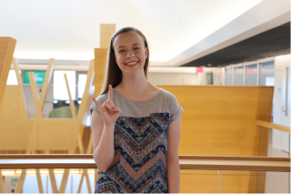 recent Honors graduate and former Tampa Judy Genshaft Honors College Student Council President Audra Nikolajski poses while making a Go Bulls sign in the Judy Genshaft Honors College