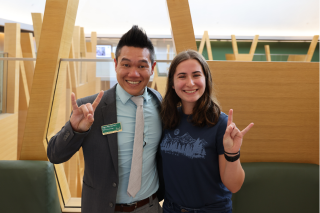 Dr. Andrew Hargrove and Morgan Mathews pose while making "Go Bulls" signs in the Judy Genshaft Honors College