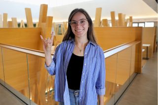 Judy Genshaft Honors College alum Brooke Casey poses while making a Go Bulls hand sign in the Honors building.