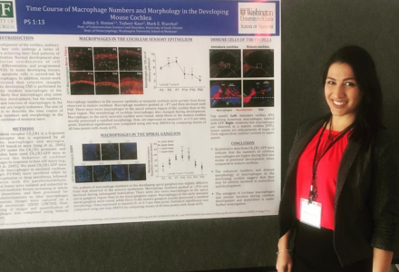 Ashley Hinton smiles while standing next to a research presentation