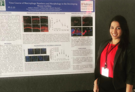 Ashley Hinton smiles while standing next to a research presentation 