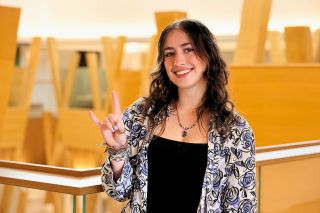 Natalie AmRhein holding up the Go Bulls hand sign in the Honors building