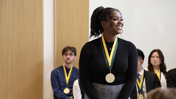 A Judy Genshaft Honors College graduate smiles after receiving ther Honors Medallion