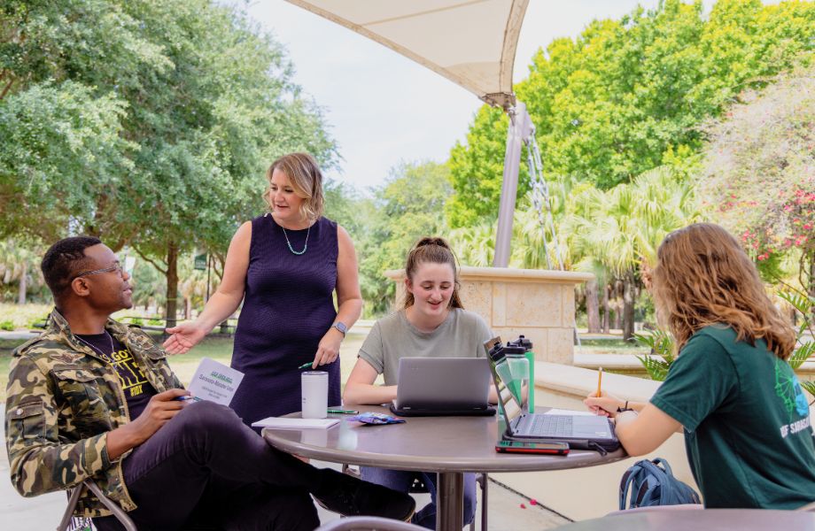 Dr. Cayla Lanier talking to students at a table outside.