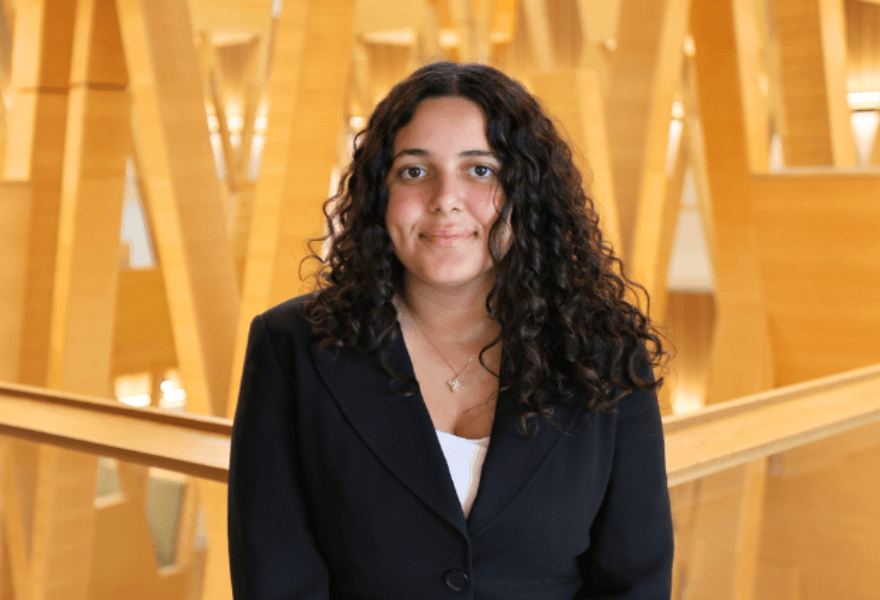 Headshot of Sophia Fahmy inside of Judy Genshaft Honors College with wood learning lofts in the background
