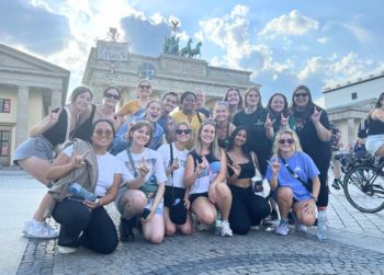 Image of a large group of Honors students and faculty posing while making Go Bulls signs linking to the Poland and Germany: The Holocaust and Europe Today study abroad program webpage.