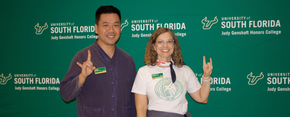 Program leads, Kevin Lee and Dr. Lindy Davidson smile infront of a USF themed backdrop.