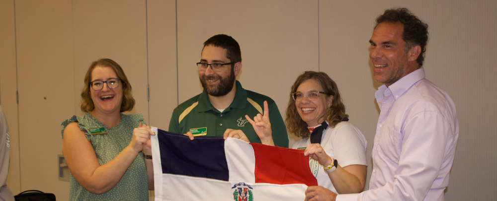 Dominican Republic leads Dr. Cayla Lanier, Joey Sousa, Dr. Lindy Davidson, and Dennis Mont'ros wave the Domincan flag over their booth at tapas night.